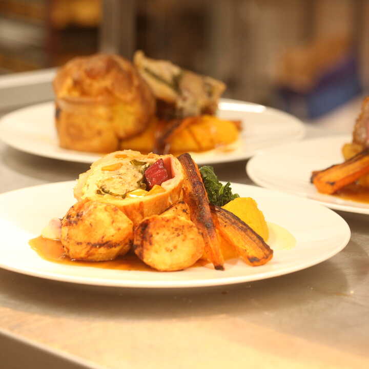 Plates of gourmet dishes, featuring meat, vegetables, and sauces, arranged on a table.