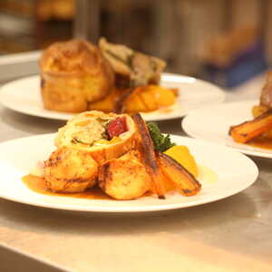 Plates of gourmet dishes, featuring meat, vegetables, and sauces, arranged on a table.